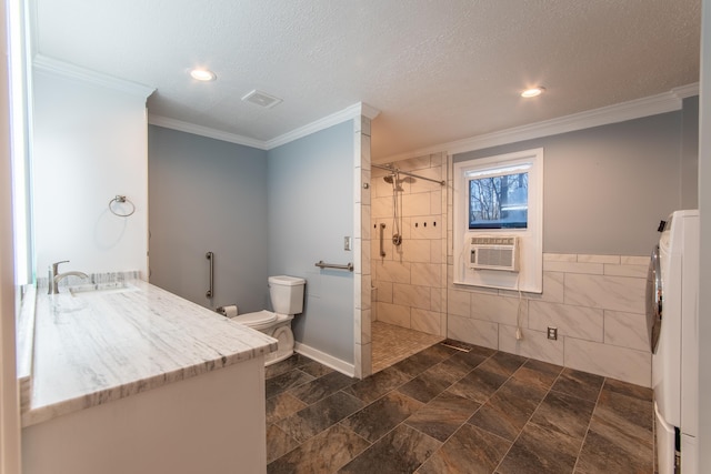 bathroom featuring toilet, tile walls, washer / dryer, ornamental molding, and sink