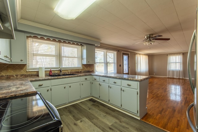 kitchen with kitchen peninsula, ornamental molding, electric range oven, and sink