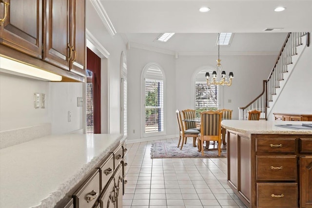 kitchen featuring hanging light fixtures, crown molding, light stone countertops, light tile patterned floors, and a notable chandelier