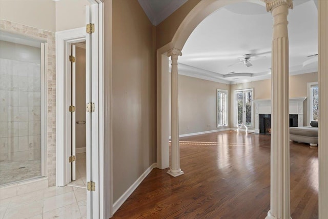 hall featuring decorative columns, ornamental molding, and light hardwood / wood-style flooring