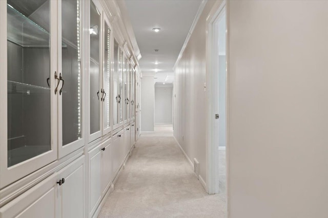 hallway featuring ornamental molding and light carpet