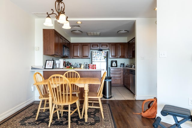 kitchen featuring white refrigerator, dishwasher, light hardwood / wood-style floors, kitchen peninsula, and pendant lighting