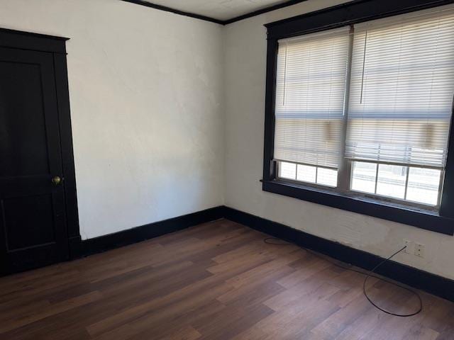 unfurnished room featuring ornamental molding and dark hardwood / wood-style flooring