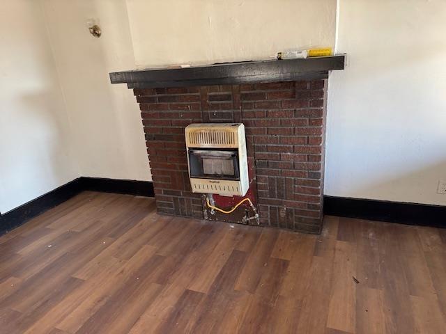 details with hardwood / wood-style flooring, a brick fireplace, and heating unit