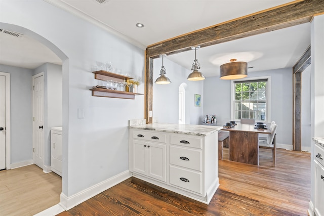 kitchen featuring washer / clothes dryer, hanging light fixtures, dark wood-type flooring, light stone counters, and white cabinetry