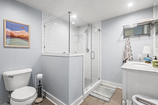 bathroom featuring a shower with door, vanity, and toilet