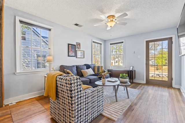 living room featuring ceiling fan, a textured ceiling, and hardwood / wood-style flooring