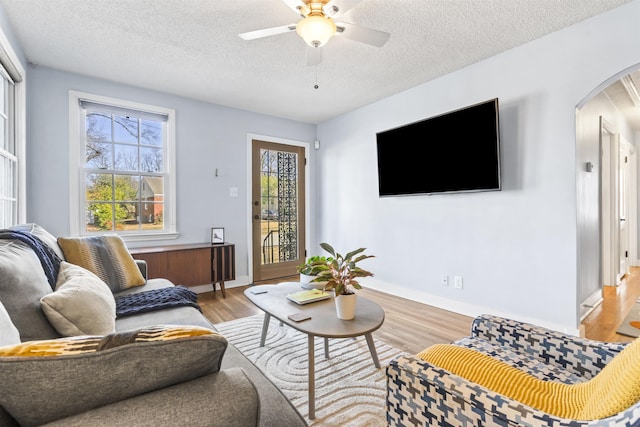 living room with a textured ceiling, ceiling fan, and light hardwood / wood-style floors