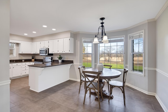 kitchen with kitchen peninsula, a chandelier, hanging light fixtures, white cabinets, and appliances with stainless steel finishes