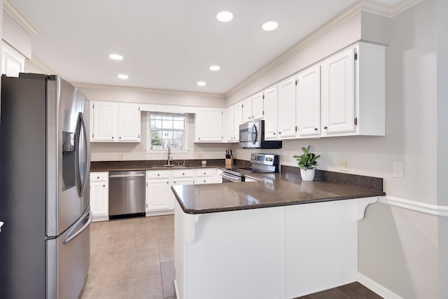 kitchen with kitchen peninsula, appliances with stainless steel finishes, and white cabinets