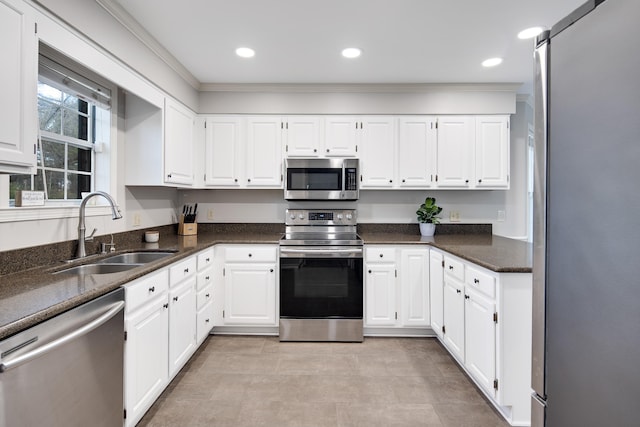 kitchen with stainless steel appliances, dark stone countertops, white cabinets, and sink