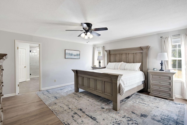 bedroom featuring a textured ceiling, ceiling fan, light hardwood / wood-style floors, ornamental molding, and ensuite bath