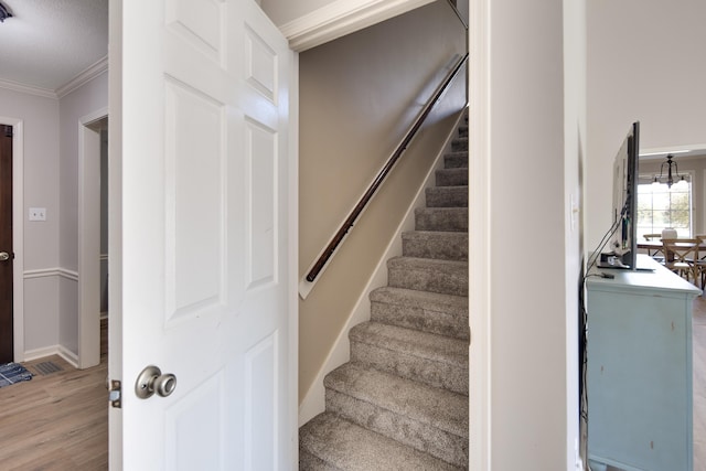 staircase with ornamental molding and hardwood / wood-style flooring