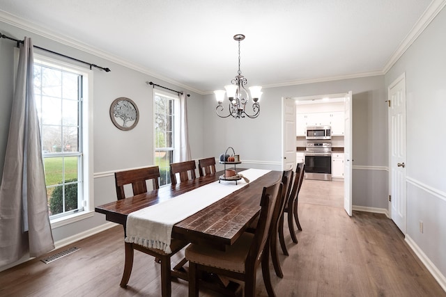 dining area featuring an inviting chandelier, light hardwood / wood-style floors, and crown molding