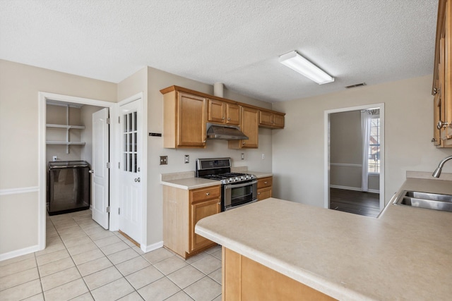 kitchen with stainless steel range with gas stovetop, kitchen peninsula, a textured ceiling, sink, and light tile patterned flooring