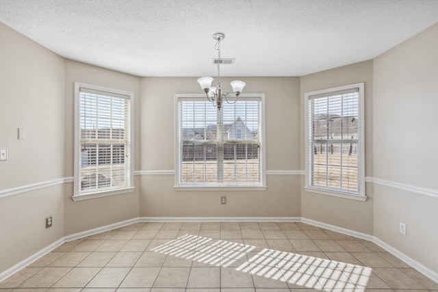 empty room featuring light tile patterned floors, a chandelier, and plenty of natural light