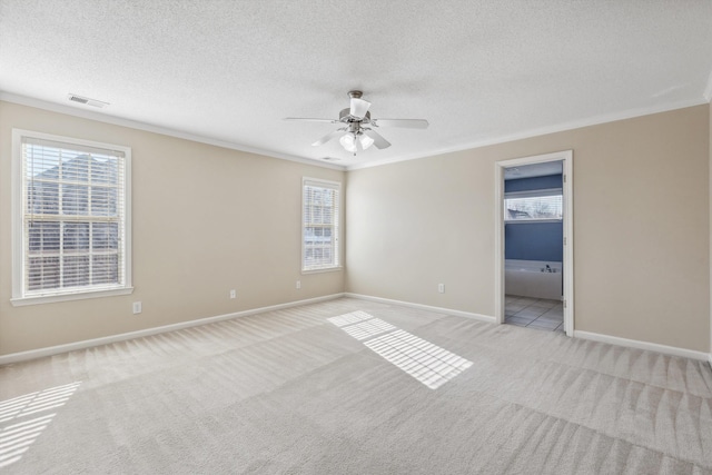 empty room featuring a textured ceiling, light carpet, ceiling fan, and crown molding