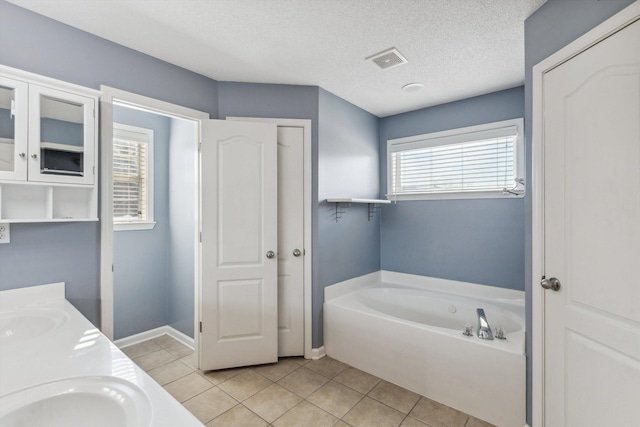 bathroom with a bathing tub, tile patterned flooring, a textured ceiling, and vanity