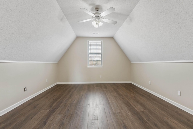 bonus room featuring a textured ceiling, ceiling fan, vaulted ceiling, and dark hardwood / wood-style floors