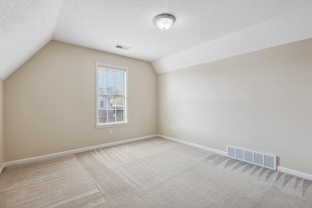 bonus room featuring a textured ceiling, vaulted ceiling, and light carpet