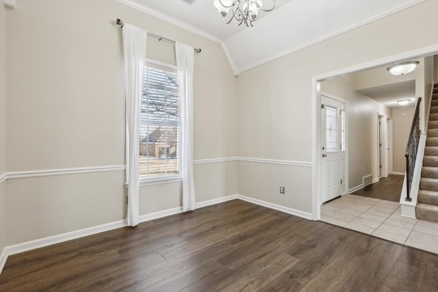 empty room with lofted ceiling, hardwood / wood-style flooring, crown molding, and a chandelier