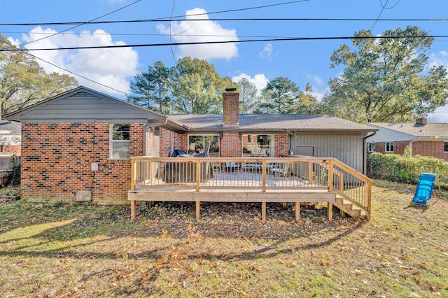 rear view of house with a deck and a lawn