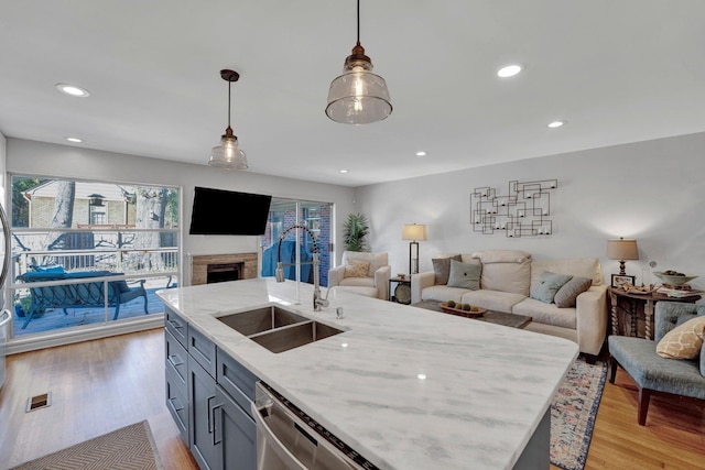 kitchen with sink, pendant lighting, light wood-type flooring, and light stone counters