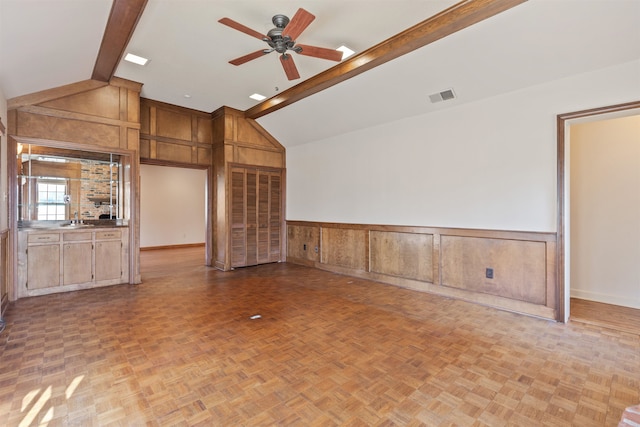 unfurnished living room with light parquet floors, ceiling fan, vaulted ceiling with beams, and sink