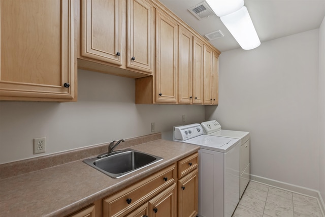 clothes washing area with sink, washing machine and dryer, and cabinets