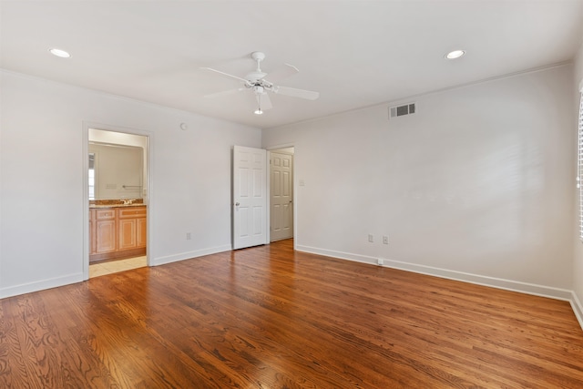 unfurnished bedroom with ensuite bathroom, ceiling fan, and hardwood / wood-style floors