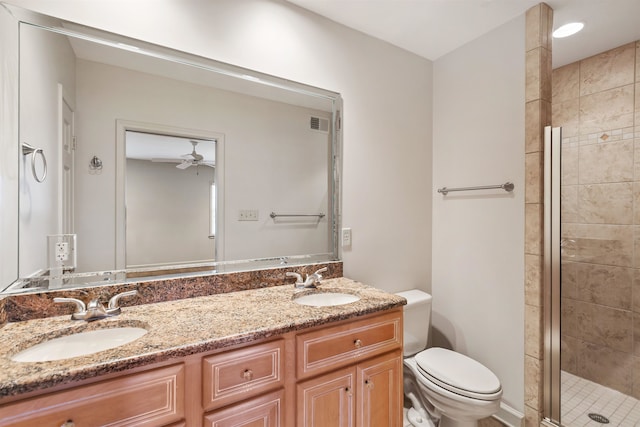 bathroom featuring ceiling fan, a shower with door, vanity, and toilet