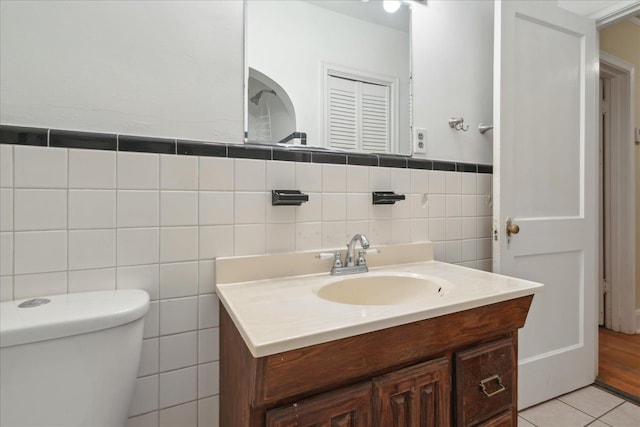 bathroom featuring tile walls, tile patterned flooring, toilet, and vanity