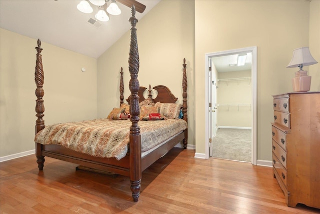 bedroom featuring vaulted ceiling, ceiling fan, wood-type flooring, a closet, and a walk in closet