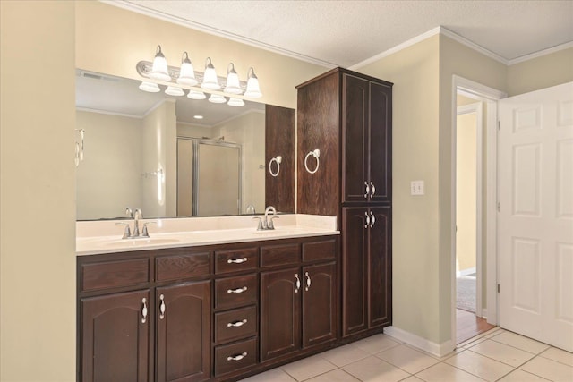 bathroom with a textured ceiling, a shower with door, crown molding, tile patterned floors, and vanity