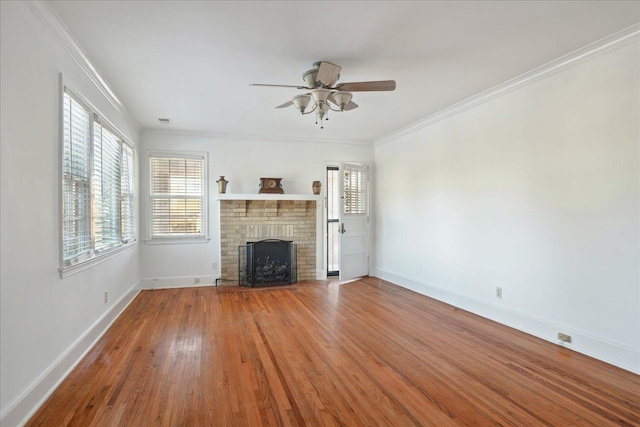 unfurnished living room featuring a brick fireplace, hardwood / wood-style floors, ceiling fan, and ornamental molding