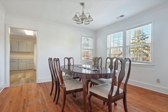 dining room featuring a chandelier, ornamental molding, and light hardwood / wood-style floors