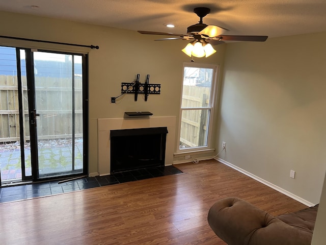 living room with a textured ceiling, ceiling fan, and dark hardwood / wood-style floors