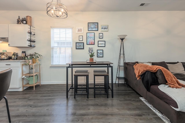 dining area with dark wood-type flooring and a notable chandelier