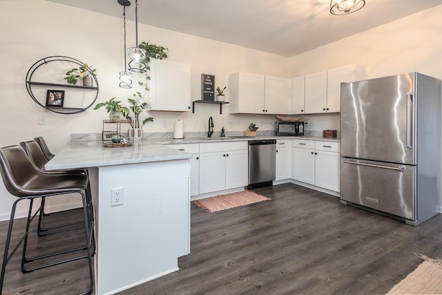 kitchen featuring appliances with stainless steel finishes, kitchen peninsula, pendant lighting, white cabinets, and sink