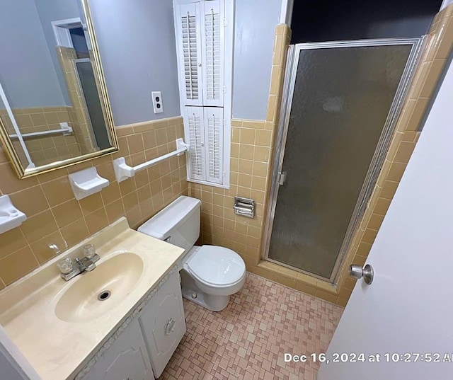 bathroom with tile patterned flooring, toilet, vanity, tile walls, and a shower with door