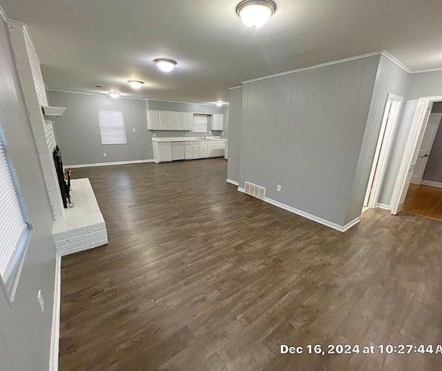 unfurnished living room with a brick fireplace, dark wood-type flooring, and ornamental molding