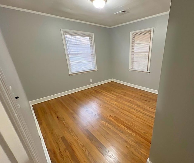 empty room featuring crown molding and hardwood / wood-style flooring