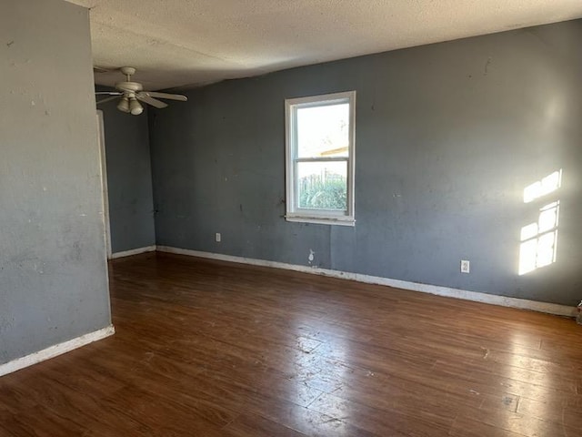 empty room with dark hardwood / wood-style flooring, a textured ceiling, and ceiling fan