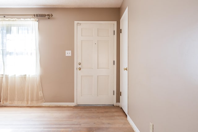 doorway to outside featuring a textured ceiling and light hardwood / wood-style flooring