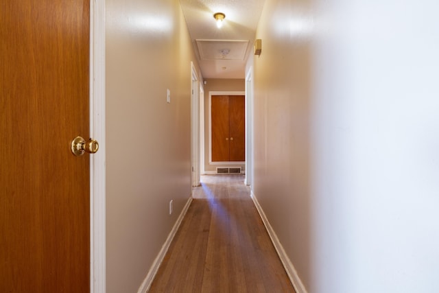 corridor with a textured ceiling and hardwood / wood-style floors