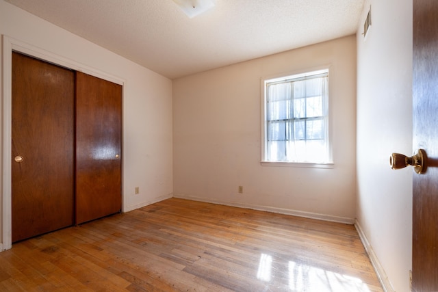 unfurnished bedroom featuring light wood-type flooring and a closet