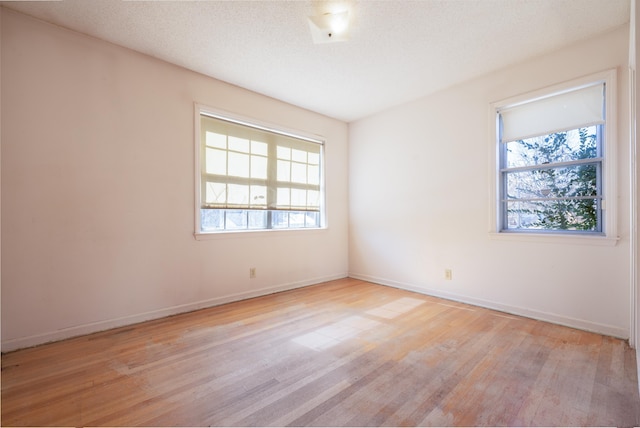 empty room with a textured ceiling and light hardwood / wood-style floors