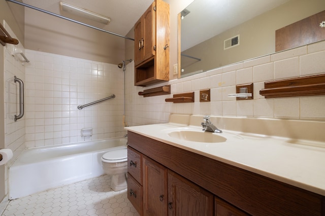 full bathroom featuring tiled shower / bath combo, toilet, vanity, tile walls, and tasteful backsplash