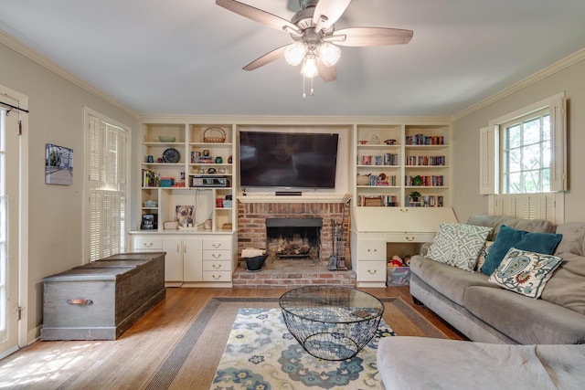 living room with wood-type flooring, a brick fireplace, ceiling fan, and ornamental molding