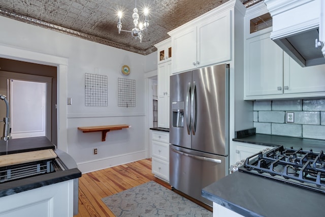 kitchen with white cabinetry, a chandelier, stainless steel fridge, decorative backsplash, and light hardwood / wood-style flooring